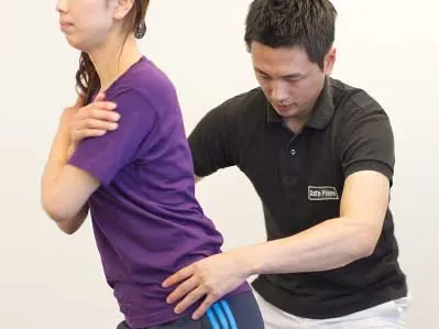 体幹をひねる動きをトレーナーが確認している様子